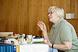 Marianne Bieker erlutert, am Tisch sitzend, wie die farbigen Ostereier hergestellt werden.