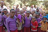 Eine Gruppe von thiopischen Kindern winkt freudig und lachend in die Kamera.
