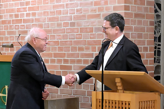 Dr. Bernhard Orlich beim Hndeschtteln mit Landeskirchenmusikdirektor Uwe Maibaum vor dem Lesepult der Trinitatiskirche.