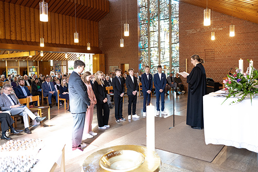 Die Noch-Konfirmandinnen und -Konfirmanden stehen mit dem Rücken zur Gemeinde vor dem Altar, wo Pfarrerin Mohr eine Ansprache an sie hält.