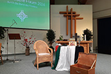 Auf dem Foto im Altarbereich der Evangeliumshalle Wehrda sind ein Stuhl, ein gedeckter Tisch und eine geffnete Truhe zu sehen.