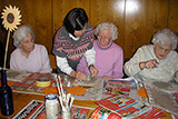 Frau Humpert mit drei Seniorinnen beim Modellieren von Ton-Blumen