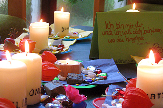 Kleine Teller, auf denen Kerzen mit den Namen der Kindergottesdienst-Kinder, Herbstfrüchte, bunte Steine und Blumen zu sehen sind.