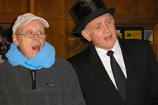 Zwei Sänger mit besonderer Kopfbedeckung bei der Chorprobe.