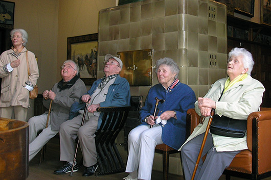 Fünf Teilnehmerinnen und Teilnehmer des Seniorenausflugs beim Betrachten von Bildern.