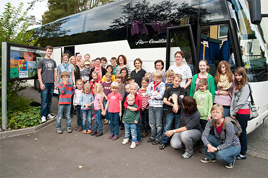 Alle Kinder, Eltern, Helferinnen und Helfer vor dem abfahrbereiten Bus.