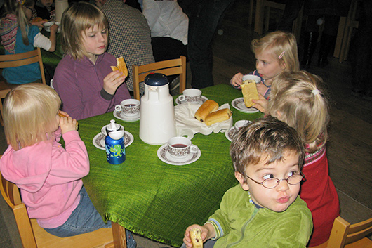 Bei Tee und Gebäck lassen es sich die Kinder am Tisch schmecken.