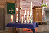 Viele Taufkerzen unterschiedlicher Größe stehen auf einem Tisch im Altarraum der Trinitatiskirche.