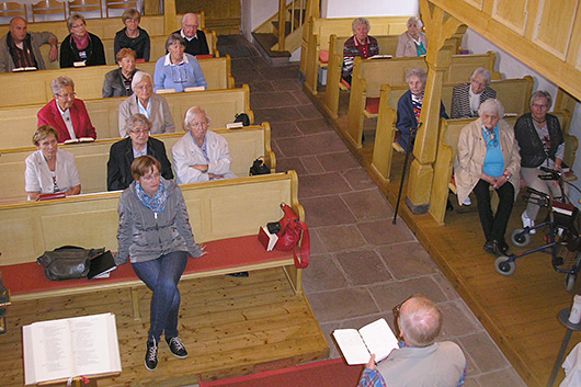 Blick von der Empore der Kirche in Unterrosphe in den Kirchraum, wo die Teilnehmerinnen und Teilnehmer des Seniorenausflugs zu sehen sind.