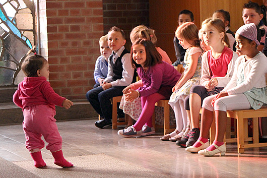 Einige Schulanfängerinnen und Schulanfänger beobachten gebannt ein kleines Kind, das im Altarraum der Trinitatiskirche läuft.