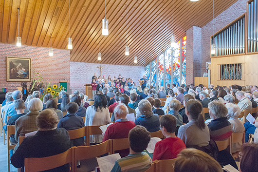 Blick von hinten in die fast bis auf den letzten Platz belegte Trinitatiskirche, wo im Altarraum die Teilnehmerinnen und Teilnehmer der Kinderkirchentage ein Lied singen.