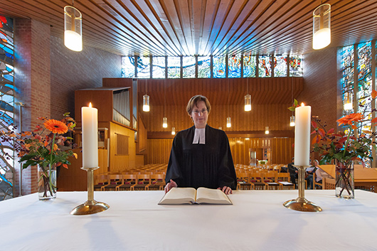 Die Pfarrerin steht vor dem Altar, auf dem die neue Altarbibel liegt.