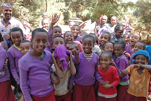 Eine Gruppe von äthiopischen Kindern winkt freudig und lachend in die Kamera.