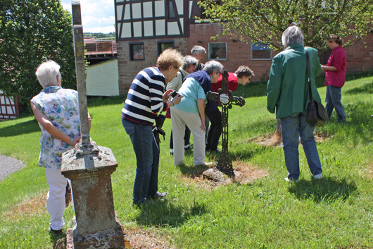 Mehrere Teilnehmerinnen und Teilnehmer des Ausflugs sind über einen Grabstein gebeugt und versuchen, die Inschrift zu lesen.