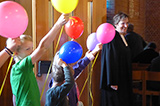 Einige Kinder bilden - ausgestattet mit bunten Luftballons - ein Spalier, durch das die Gottesdienstbesucher/inn/en nach dem Gottesdienst die Kirche verlassen werden.