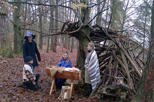 Szenenbild aus dem diesjährigen Krippenspiel: Vor einem improvisierten Stall im Wald sind der kleine Hirte, der große Räuber, Maria, Josef und das Jesuskind zu sehen.