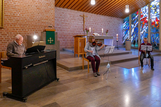 Blick in den Altarraum, wo das Trio beim Musizieren zu sehen ist.