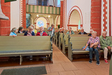 Die Teilnehmer*innen am Ausflug im Rahmen des Gemeindetreffs sitzen auf den Kirchenbänken der Nikolaikirche in Caldern und hören den Ausführungen von Pfr. Ruckert zu.