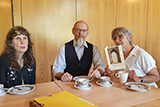 Drei Teilnehmer*innen sitzen nach dem Gottesdienst an einem Tisch im großen Gemeinderaum und unterhalten sich beim Kirchencafé.