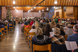 Blick aus dem hinteren Teil des bis auf den letzten Platz gefllten Gottesdienstraums in Richtung Altar, wo ein Groteil der Kinder und Jugendlichen in einer Szene des Krippenspiel zu sehen ist.