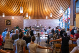 Aufnahme aus dem hinteren Teil der Trinitatiskirche in Richtung Altarraum. Die Gottesdienstbesucherinnen und Besucher machen stehend Bewegungen zu einem Lied.