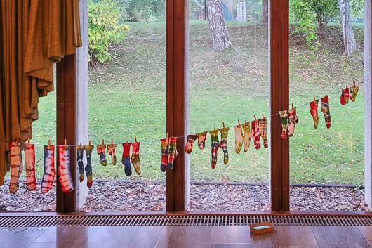 Im Groen Gemeinderaum hngen frisch gebatikte Socken zum Trocknen auf einer Leine vor dem Fenster.