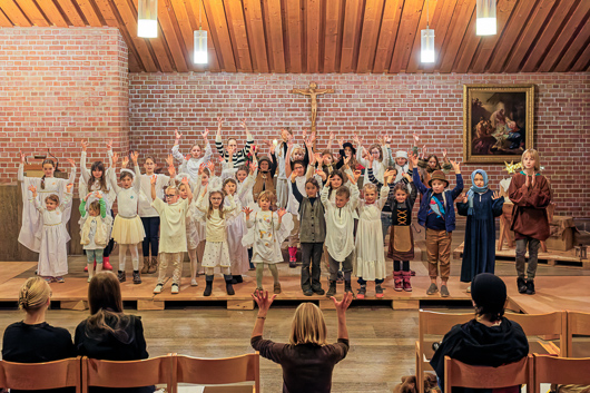 Die teilnehmenden Kinder am Krippenspiel 2025 haben zur bewegten Begleitung des eigenen Gesangs ihre Arme in die H�he gereckt.